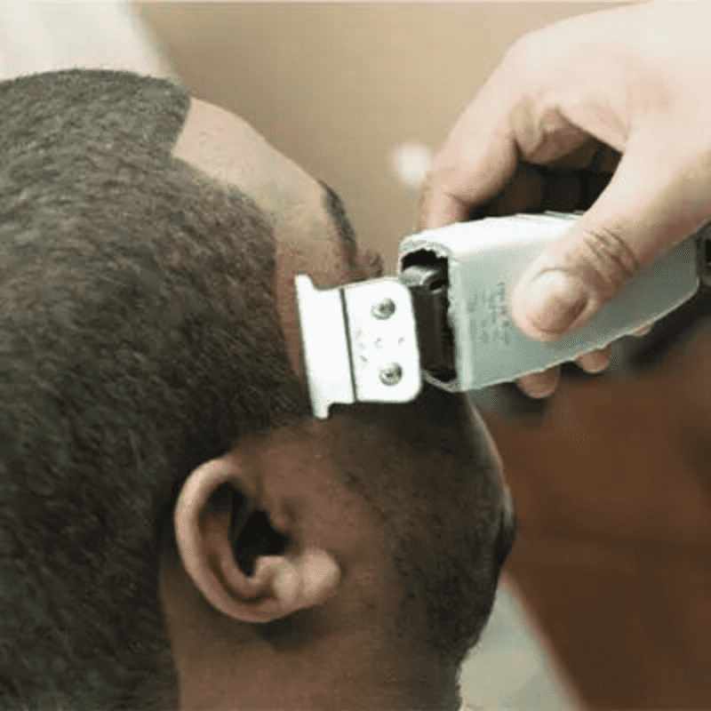 A barber lining up a client's sideburns