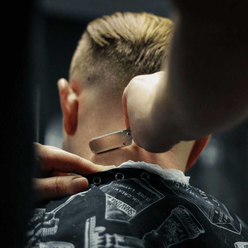 A client having his neckline shaved by a barber holding a razor